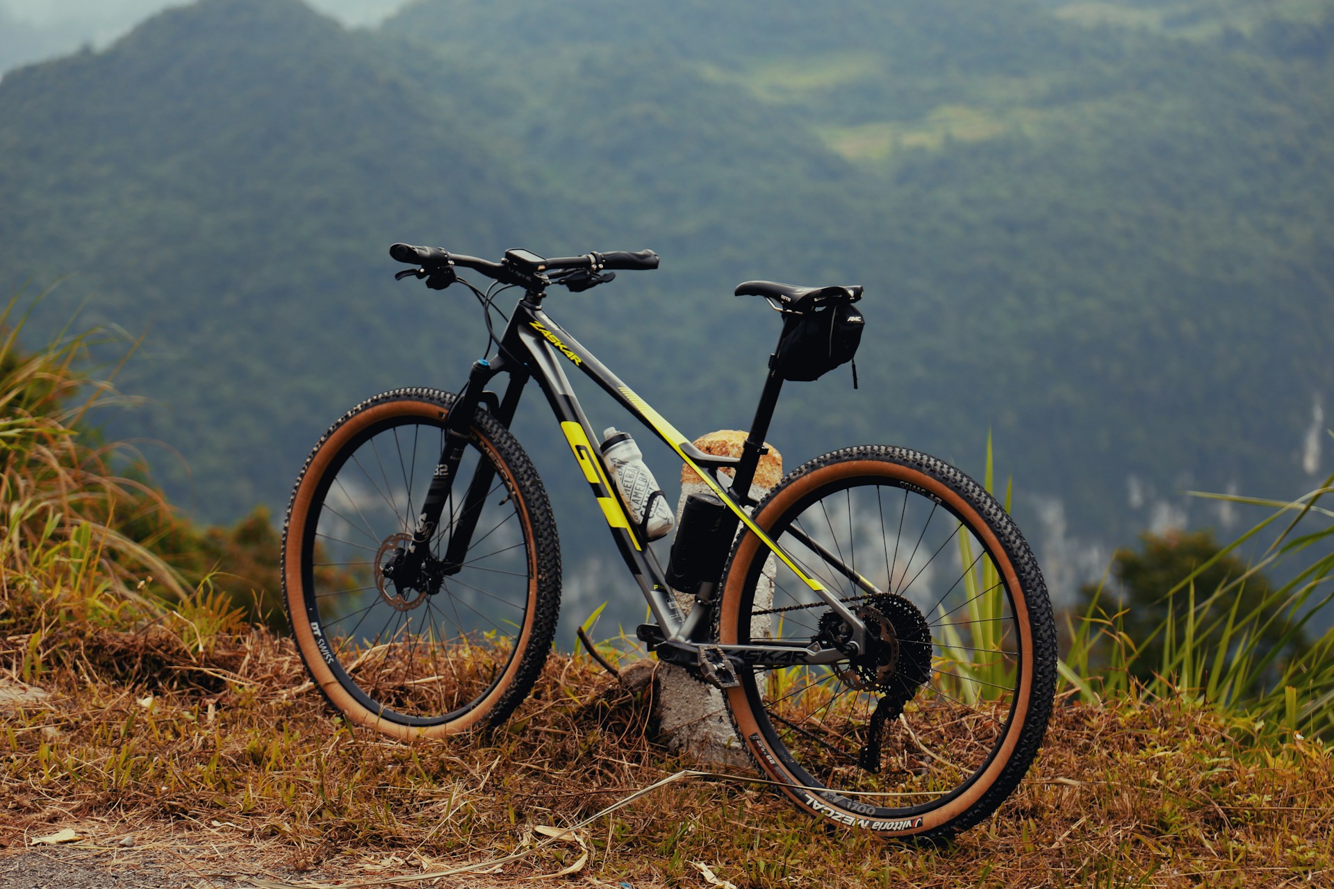 a bicycle parked on top of a grass covered hillside