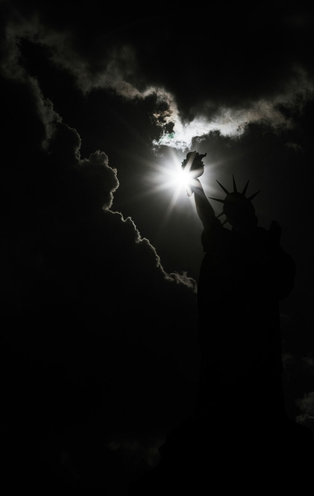 the statue of liberty is silhouetted against a cloudy sky