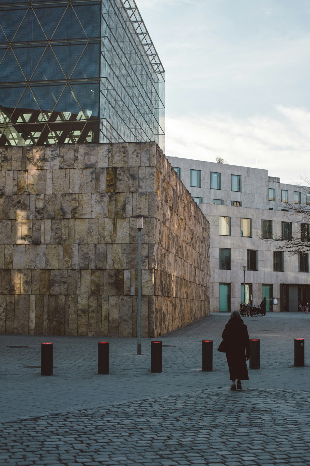 a woman walking down a street next to a tall building