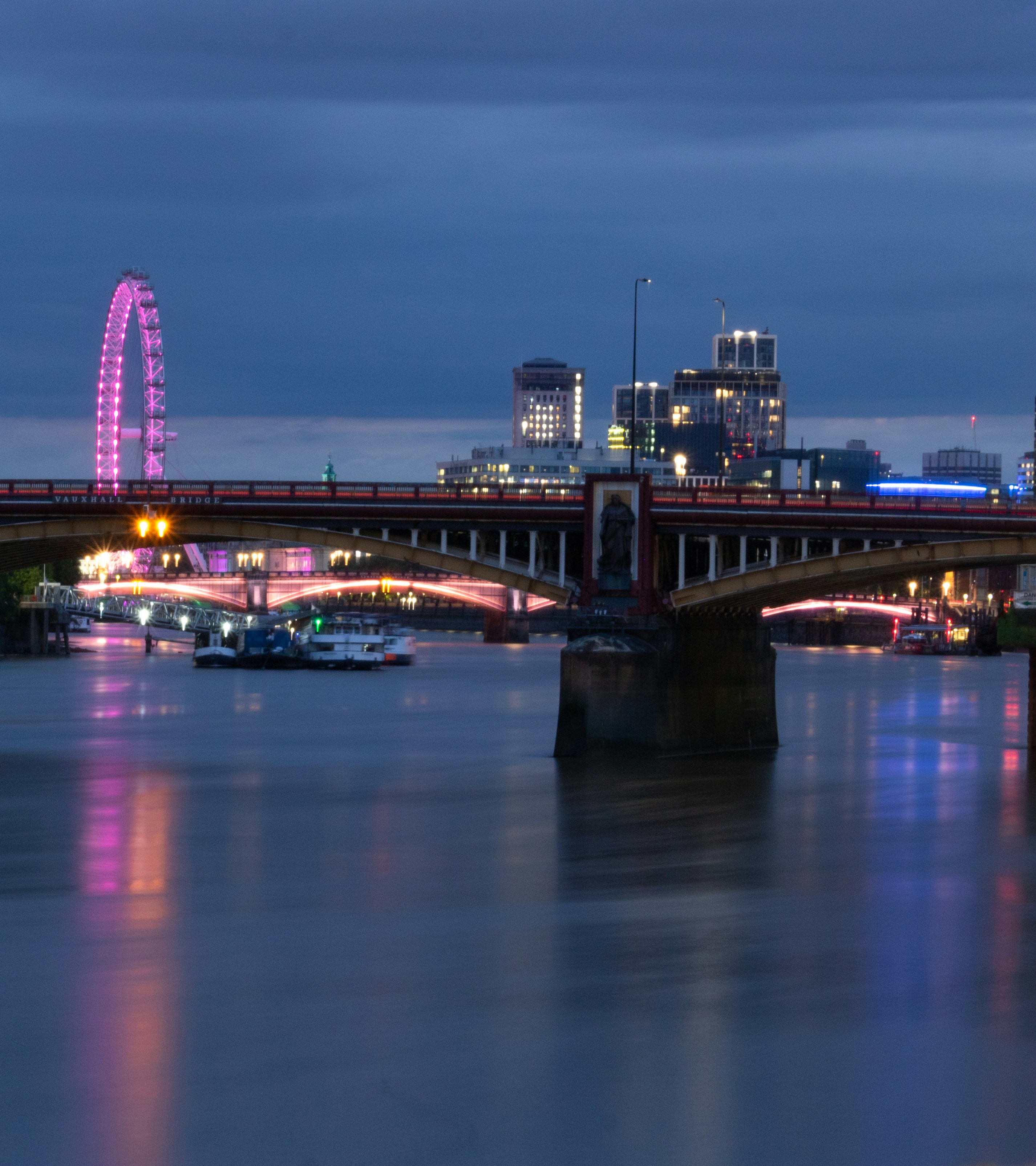 a bridge over a river with a ferris wheel in the background