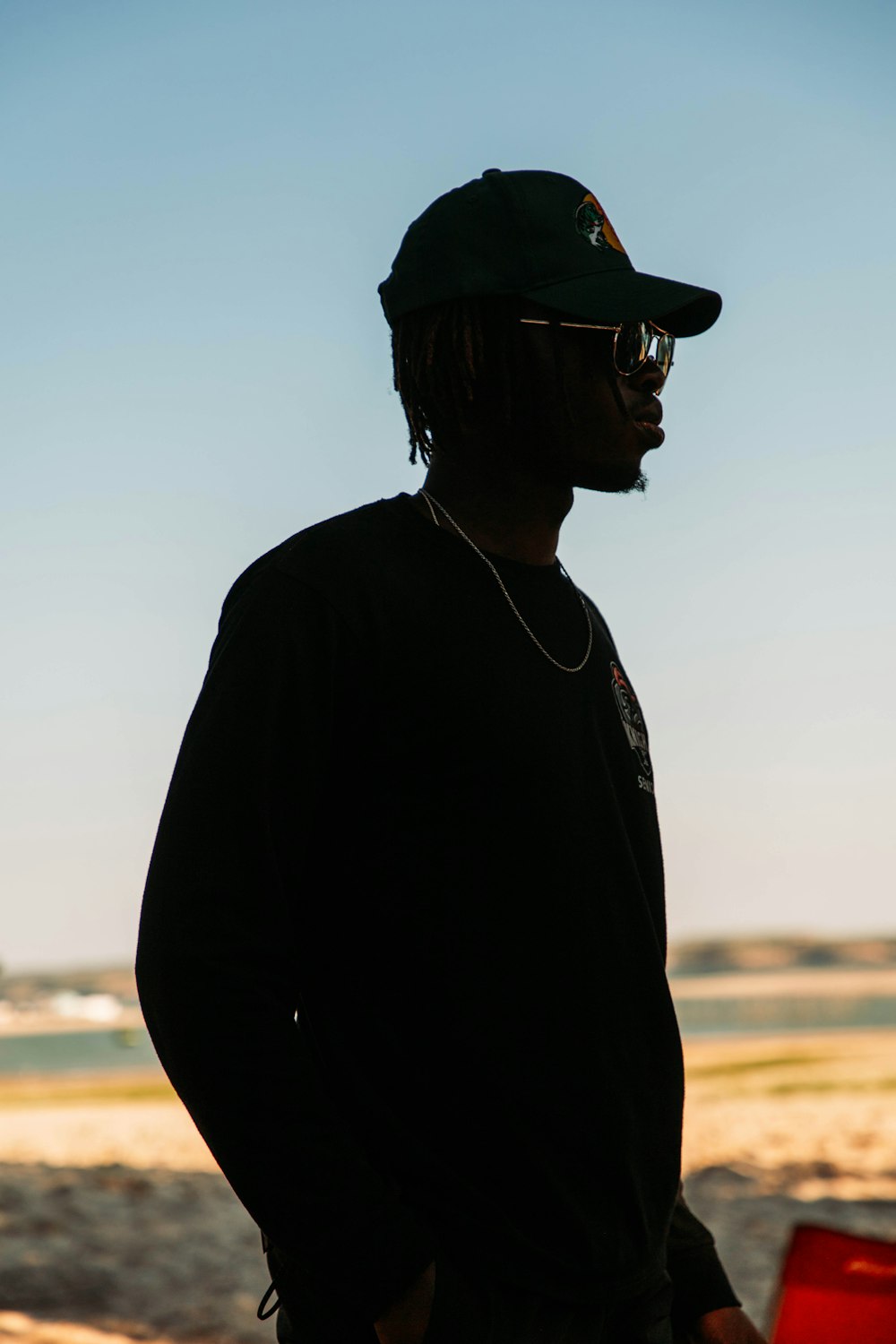 a man with a hat and sunglasses standing on the beach