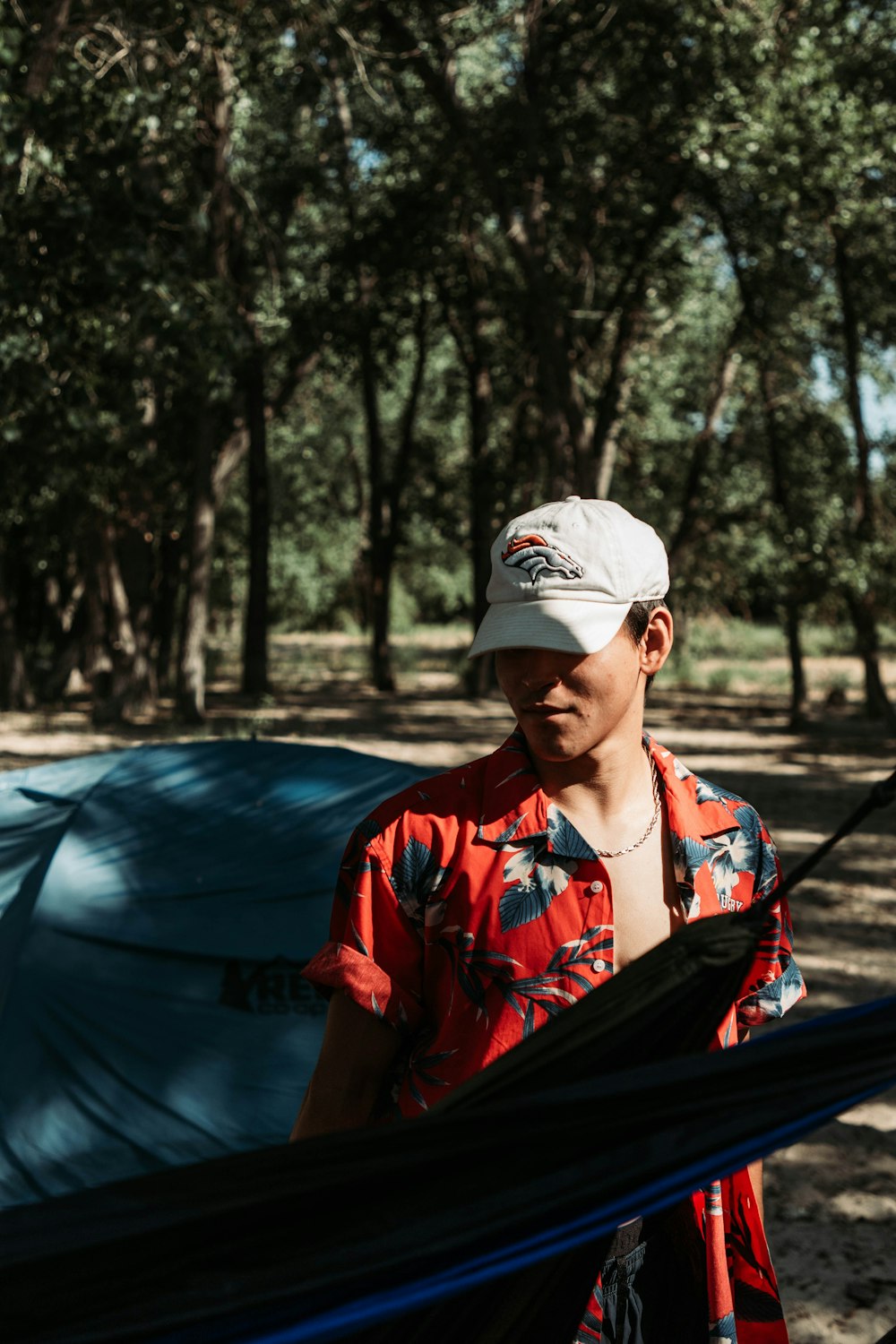 a man standing next to a tent in the woods