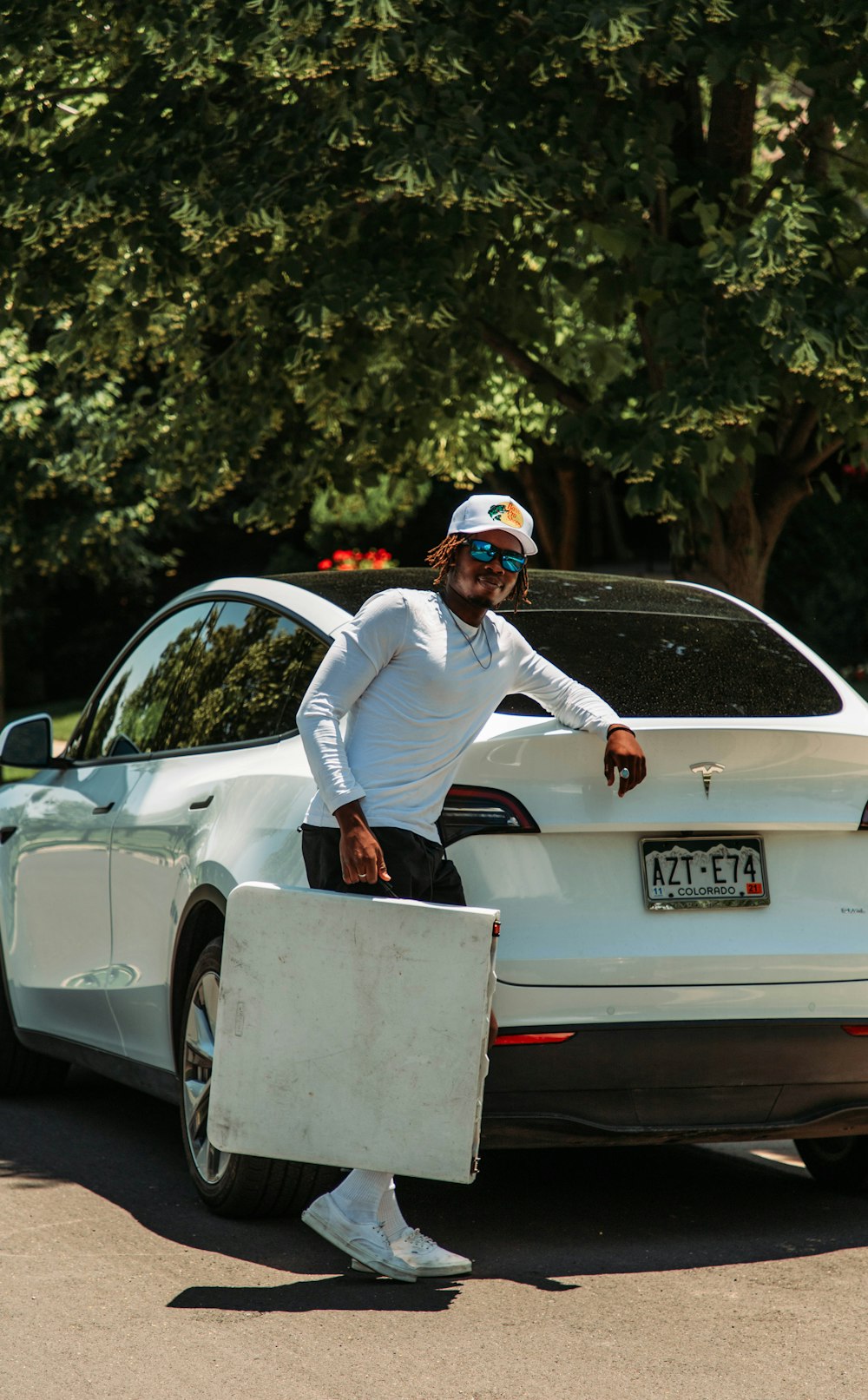 a man in a white shirt and black pants standing next to a white car