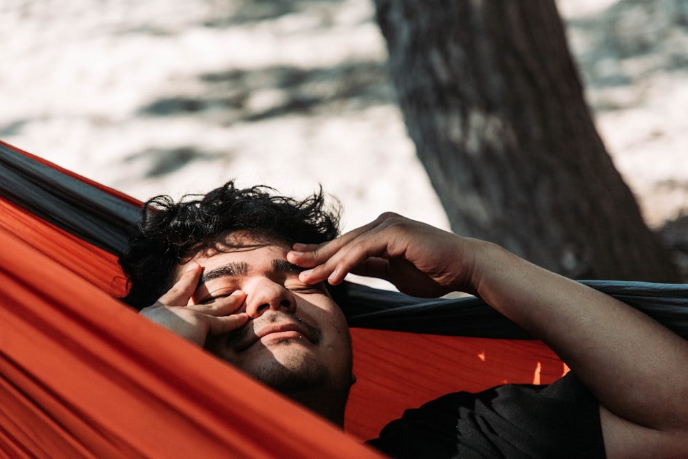 a man laying in a hammock with his eyes closed