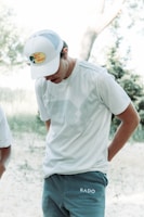 Model wearing a minimalist white t-shirt with a subtle American Teeworks logo outdoors.