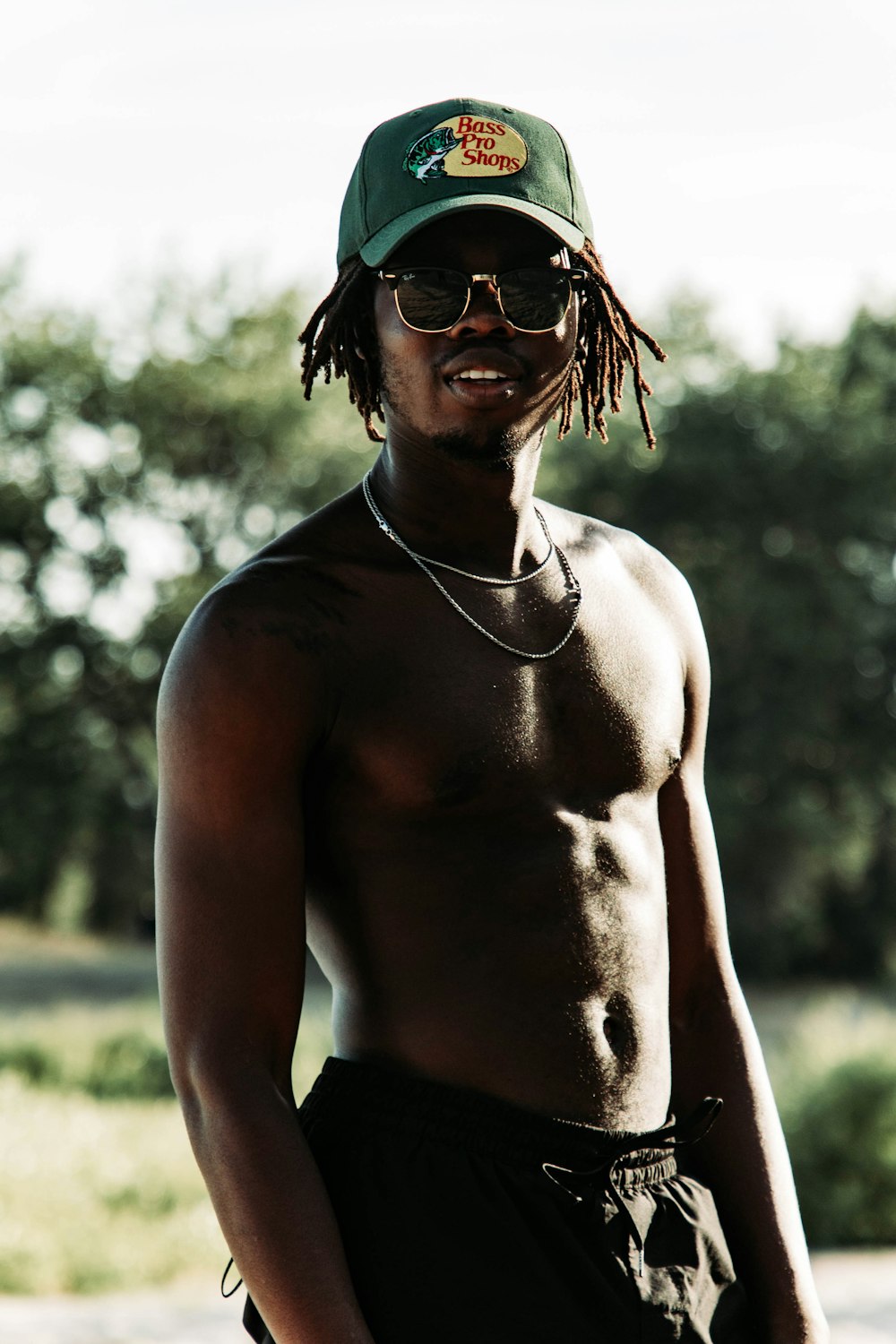 a shirtless man wearing a green hat and sunglasses