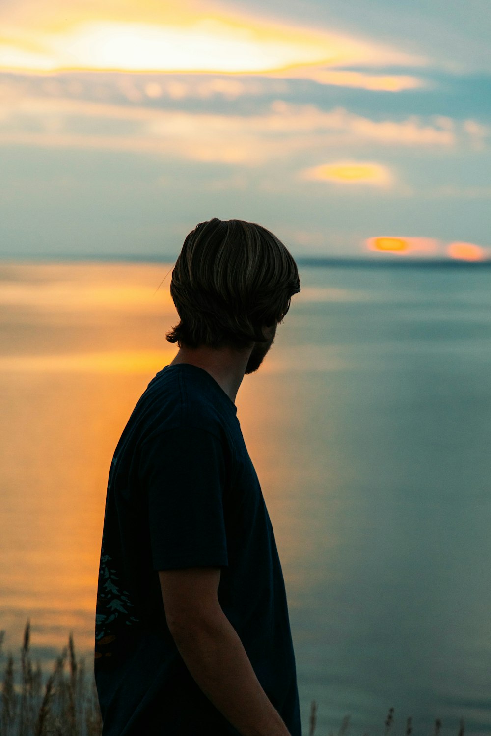 a man standing on top of a hill next to the ocean