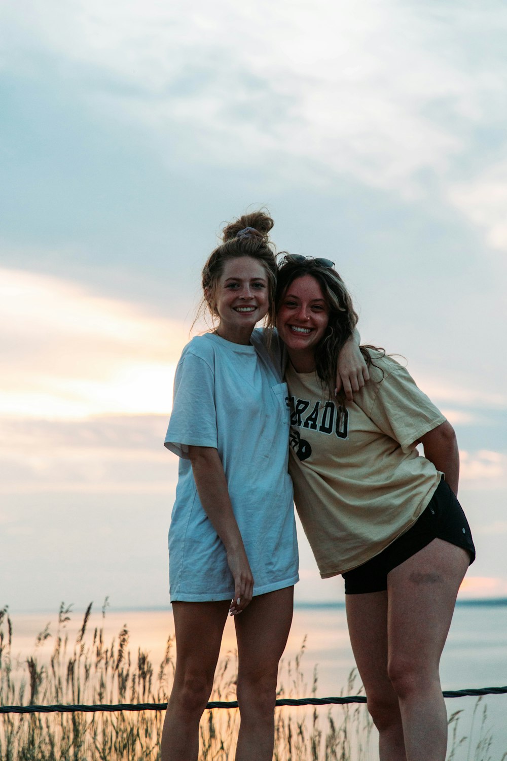 two girls standing next to each other near the water