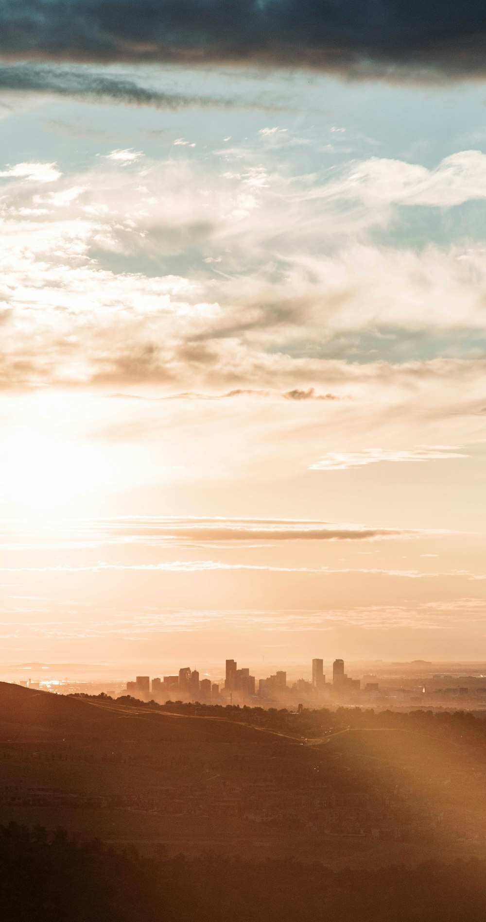 a view of a city from a hill at sunset