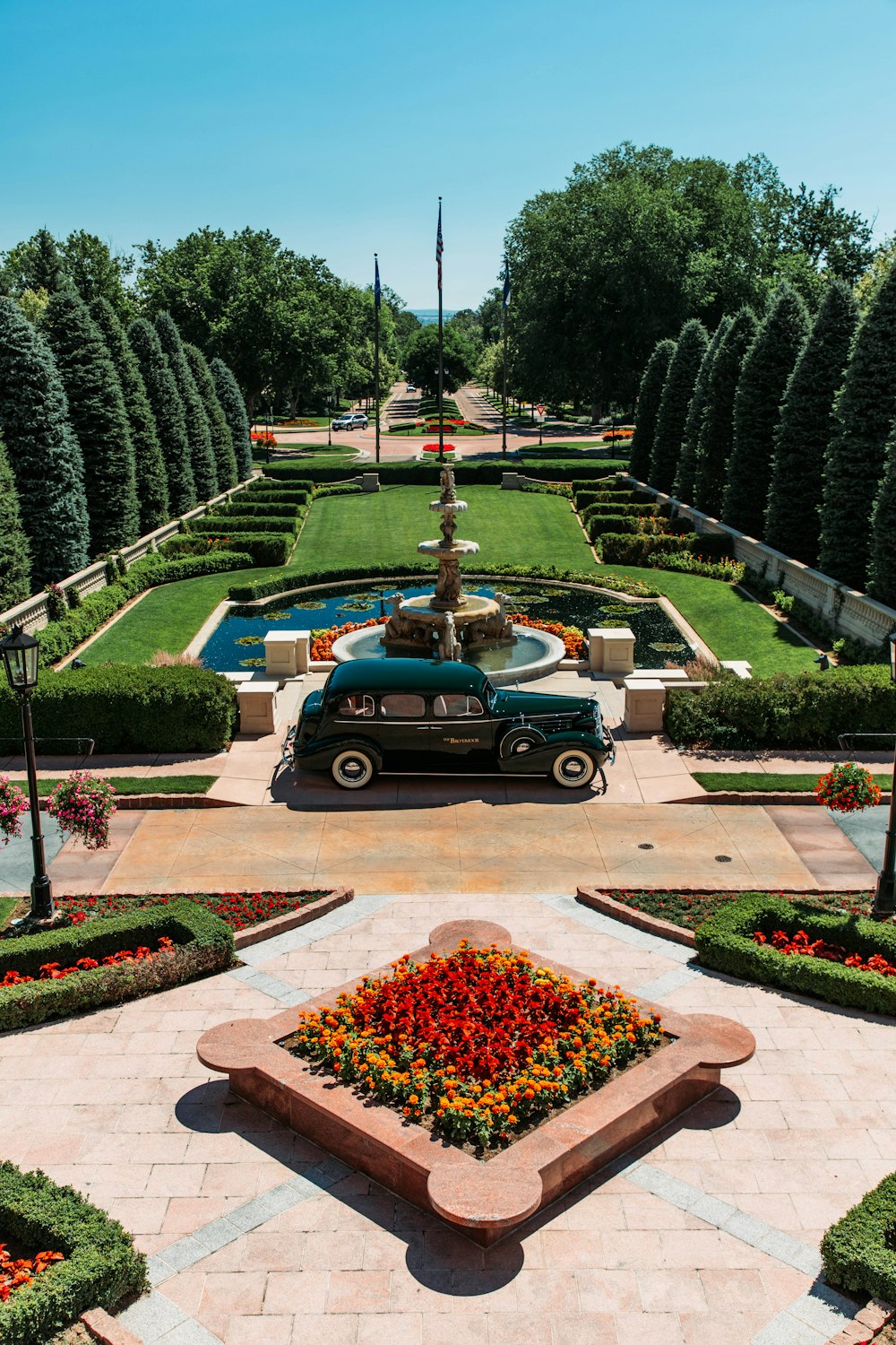 an old car parked in front of a garden