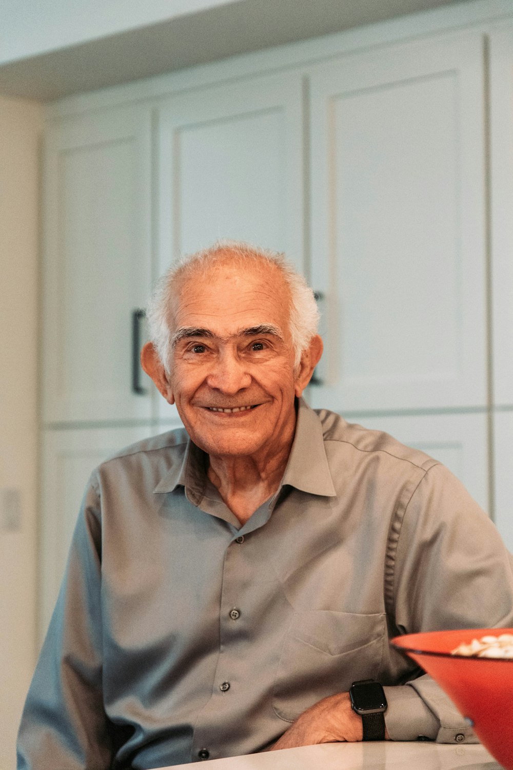 a man sitting at a table with a red bowl in front of him