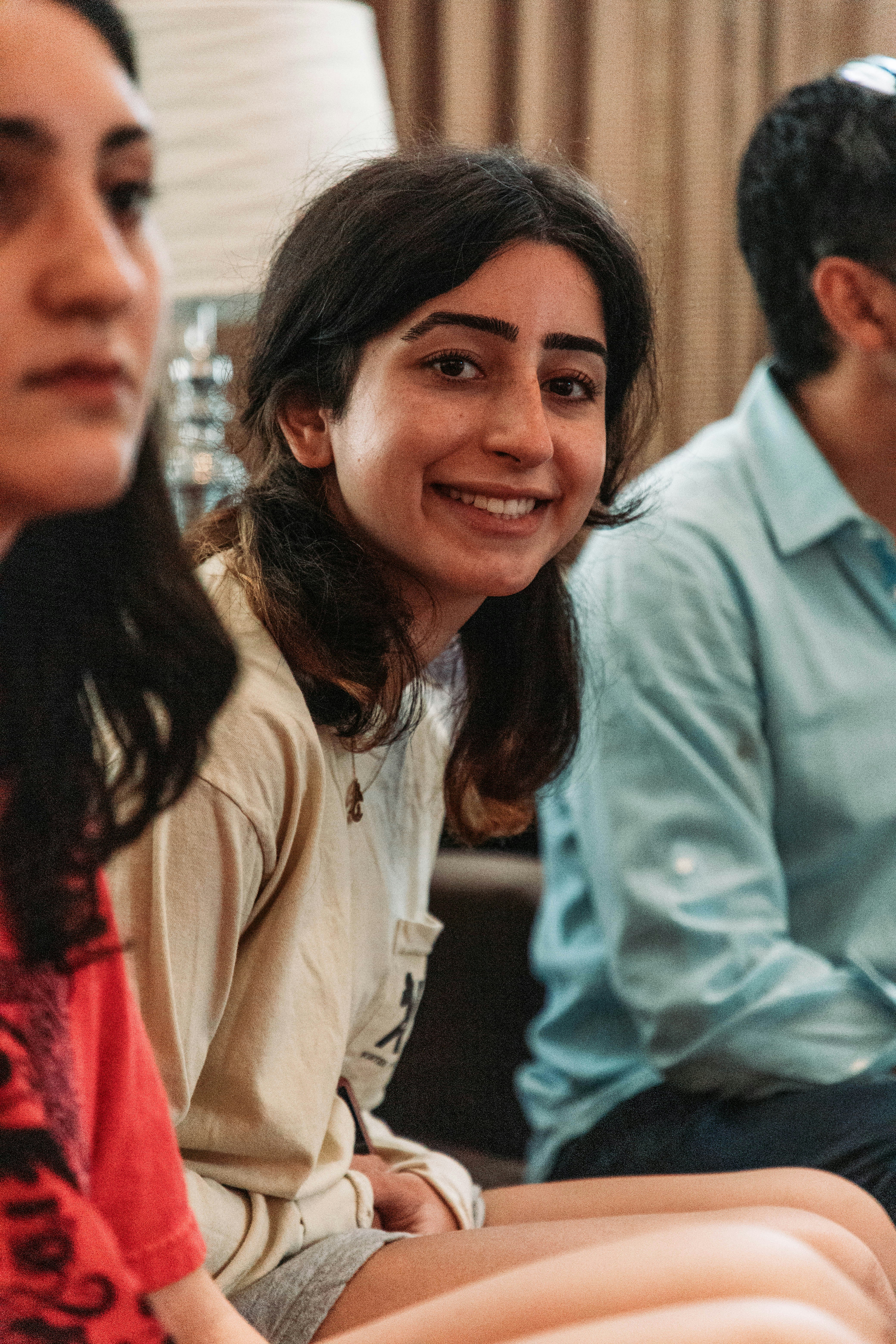 A warm, welcoming community health worker engaging with young people in a bright, friendly setting.