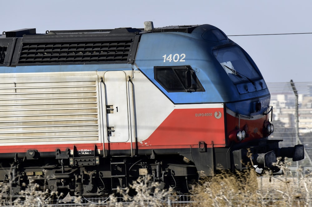 a blue and red train traveling down train tracks