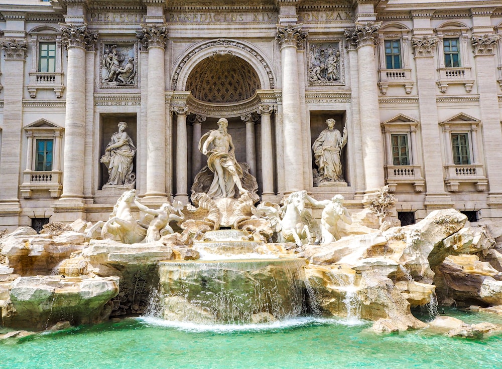 a fountain in front of a building with statues on it