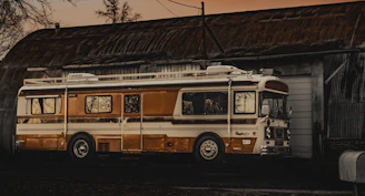 A charming vintage bus parked outside a rustic countryside venue at sunset.