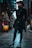 A person dressed in a dark, stylish outfit with a hat stands confidently in an urban alleyway. The cobbled path and architecture convey a modern, city atmosphere. The individual has a long beard and is wearing ornate boots, a tailored coat, and a brimmed hat, exuding a gothic or steampunk fashion sense.