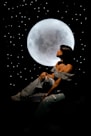 a woman sitting on a bed in front of a full moon