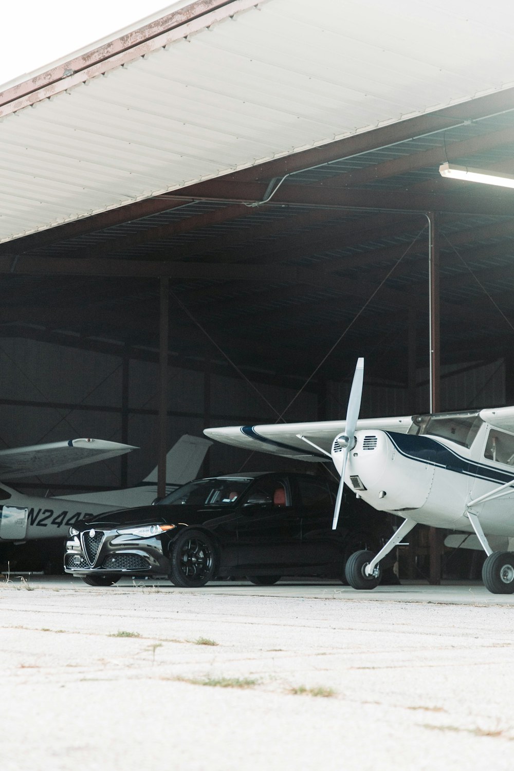 a small airplane parked in a garage next to a car