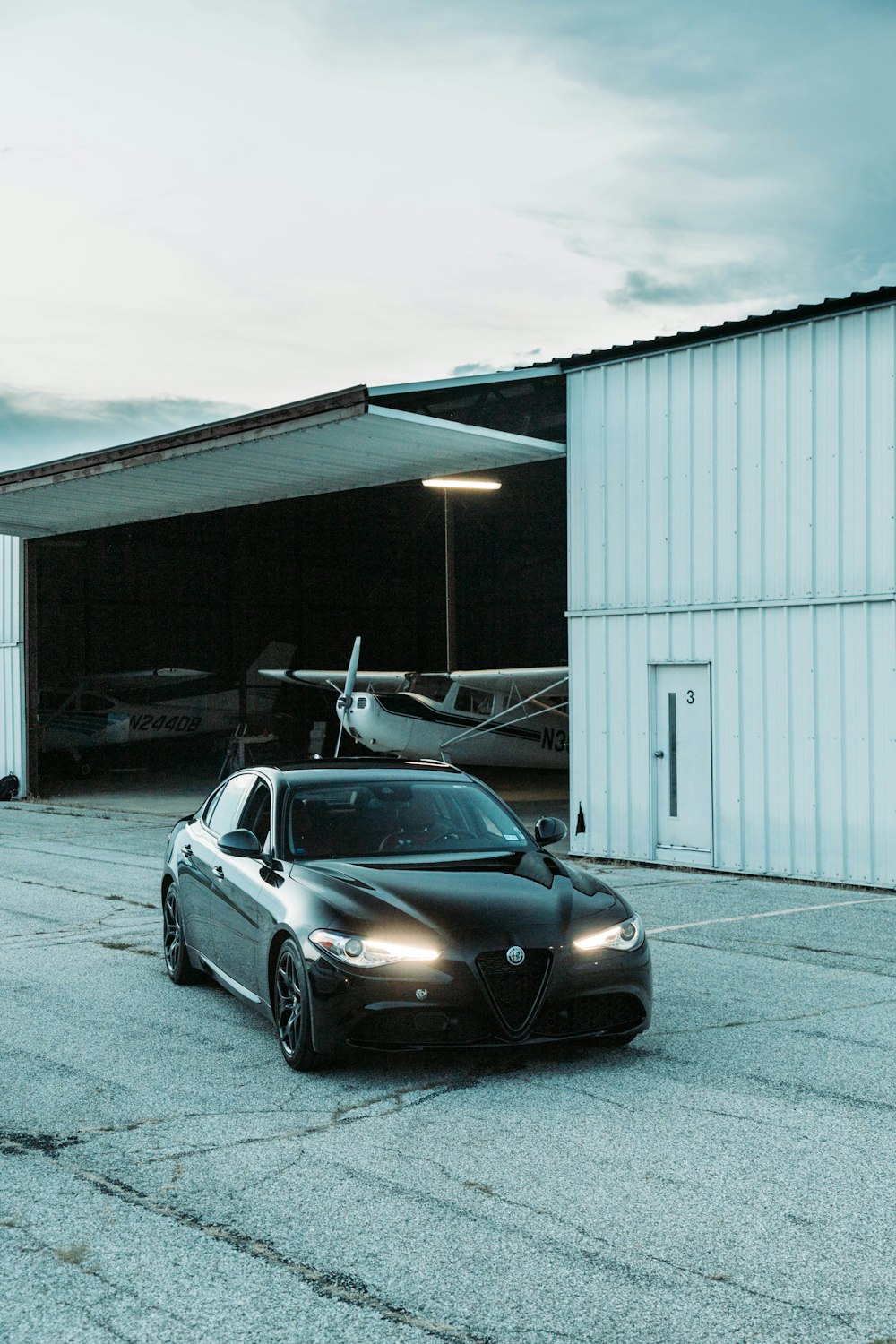 a black car parked in front of a hangar