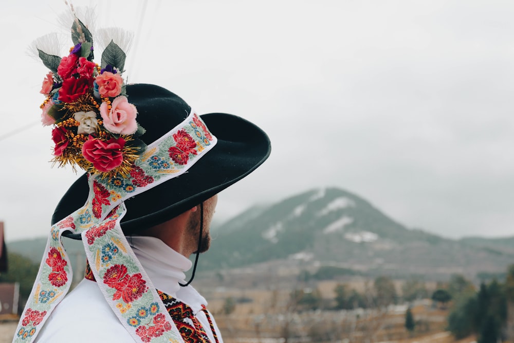 a man wearing a black hat with flowers on it