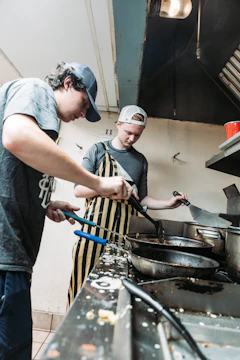 Two brothers working together fixing a residential kitchen sink.