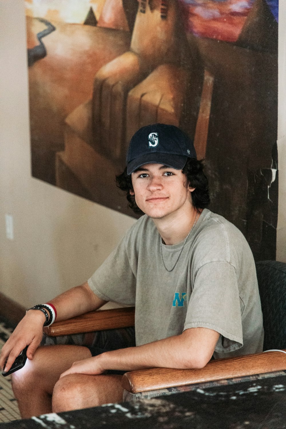 a boy sitting in a chair with a baseball cap on