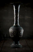 A vintage-style vase with intricate patterns displayed on a rustic wooden table.
