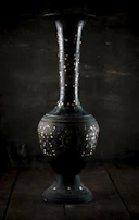 Vintage-style copper vase with subtle patina on a matte black surface.