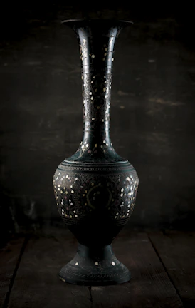 A vintage-style vase with intricate patterns displayed on a rustic wooden table.