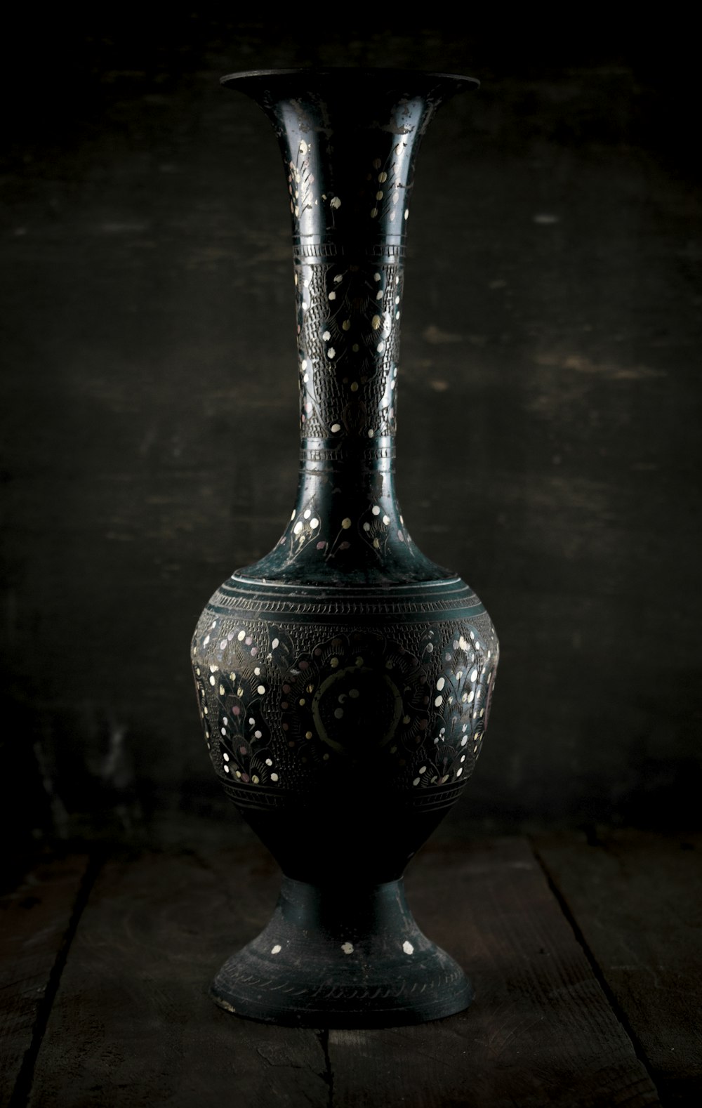 a black vase sitting on top of a wooden table
