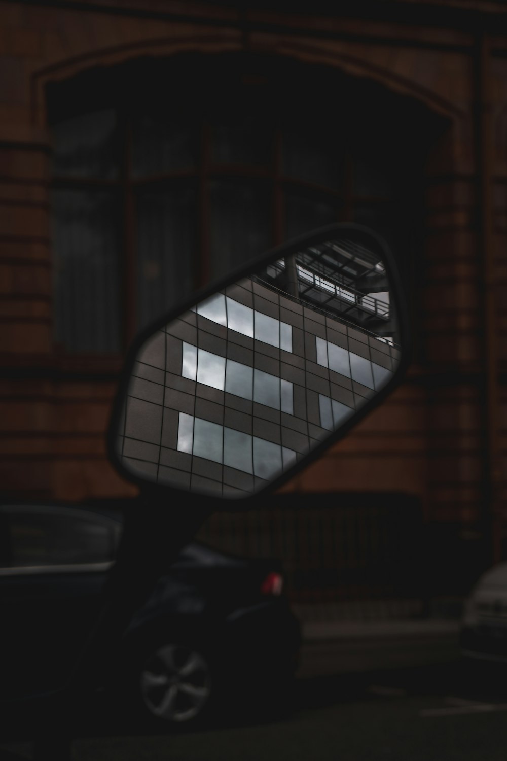 a side view mirror reflecting a building and cars