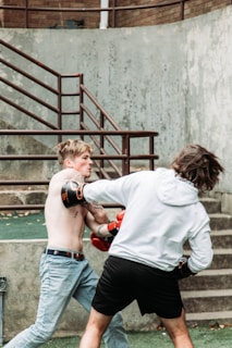two young men are practicing boxing outside