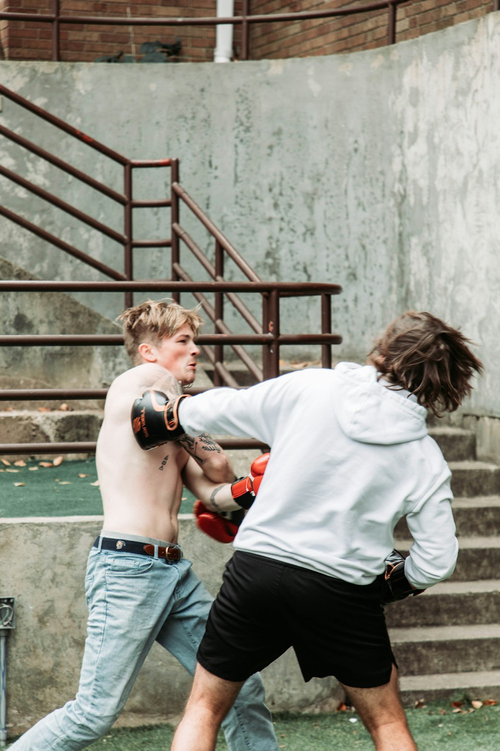 two young men are practicing boxing outside