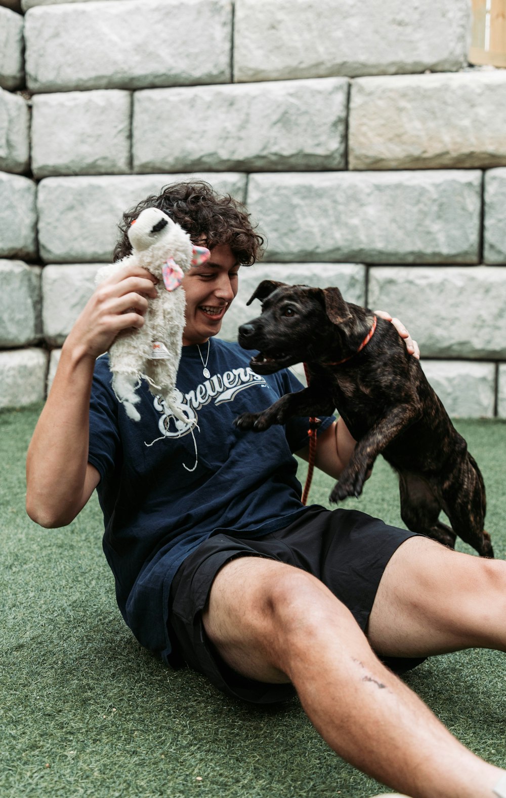 Ein Mann sitzt mit einem Hund und einem Stofftier auf dem Boden