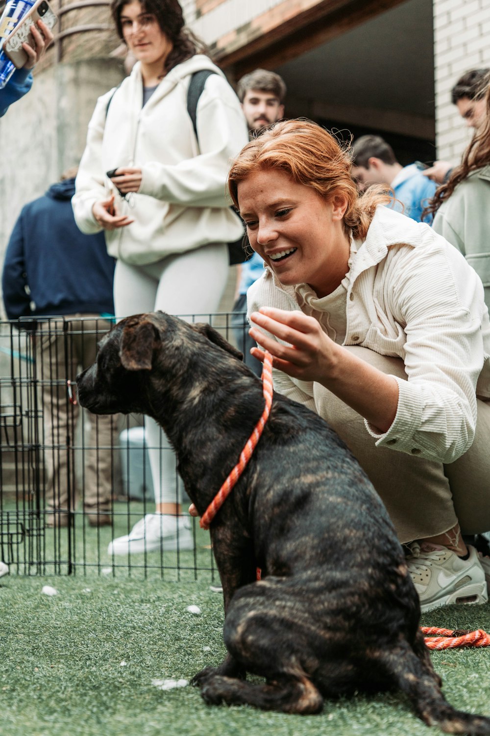 a woman kneeling down next to a black dog