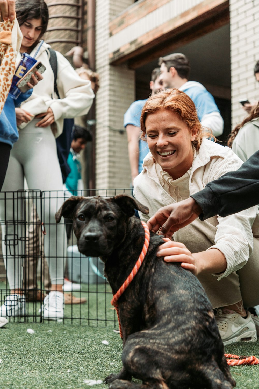 a woman petting a black dog on a leash