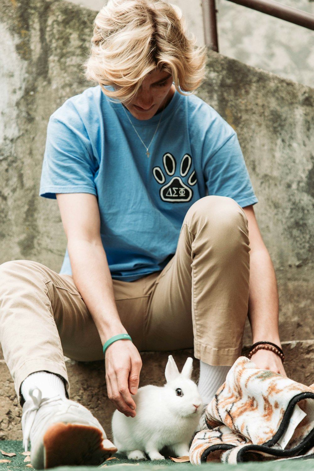 a person sitting on the ground petting a small white rabbit