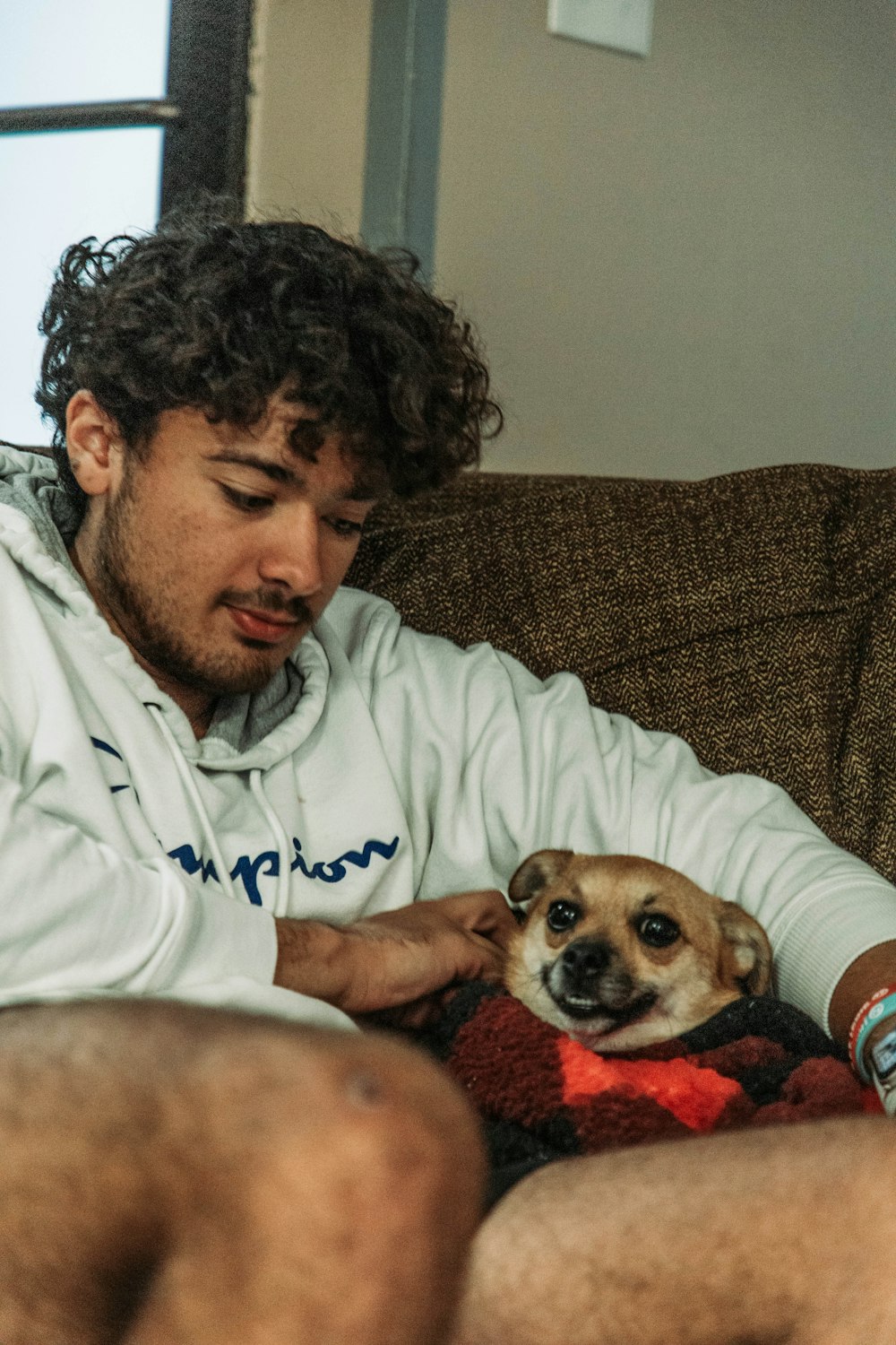 Ein Mann sitzt auf einer Couch und hält einen Hund in der Hand