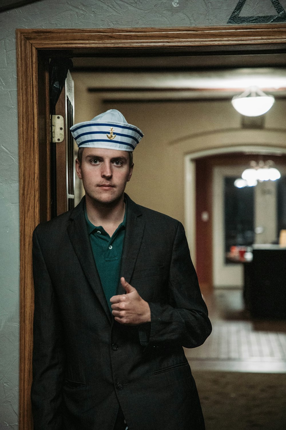 a man in a suit and hat standing in front of a mirror