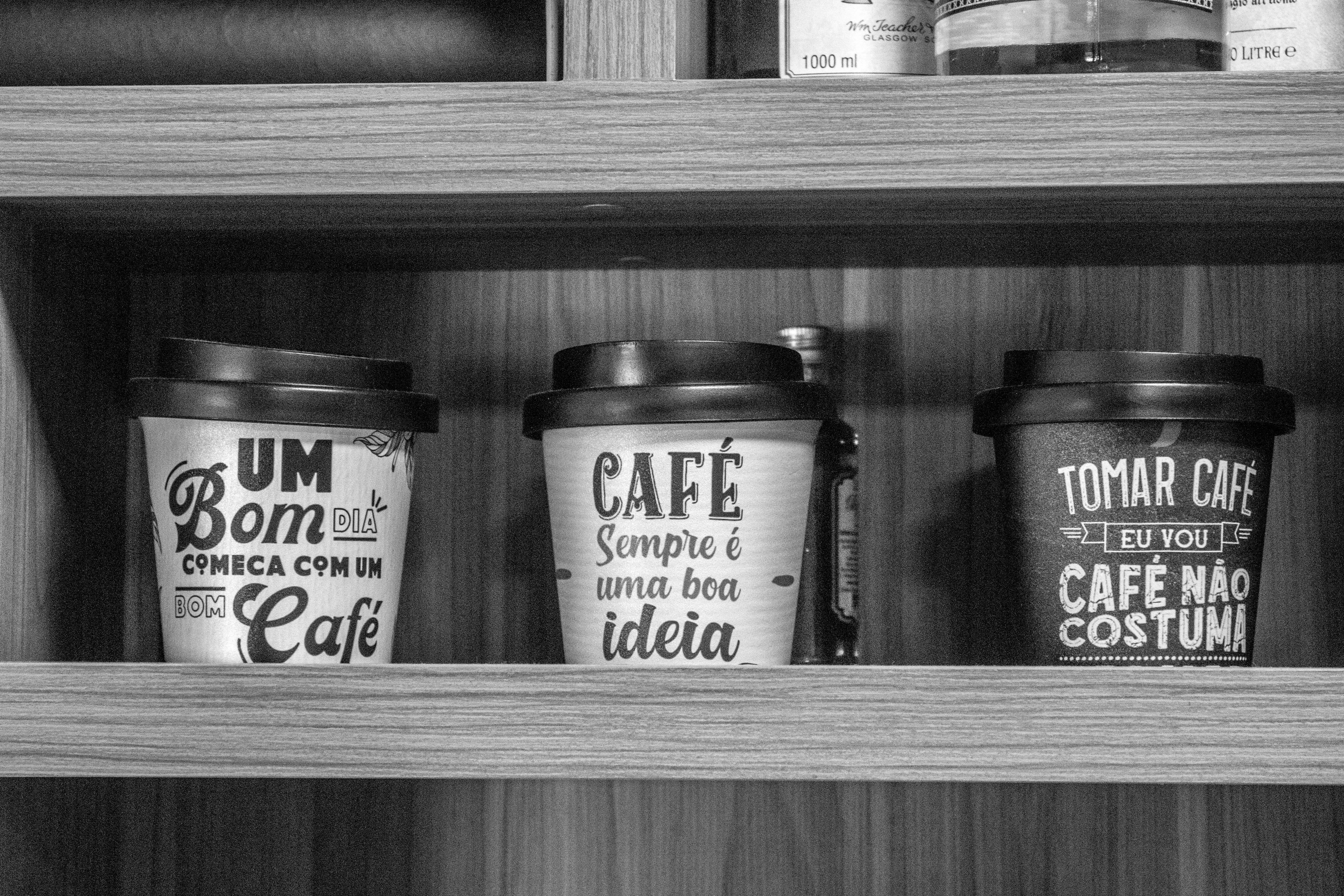 three coffee cups sitting on top of a wooden shelf