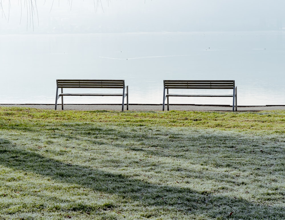 a couple of benches sitting on top of a grass covered field