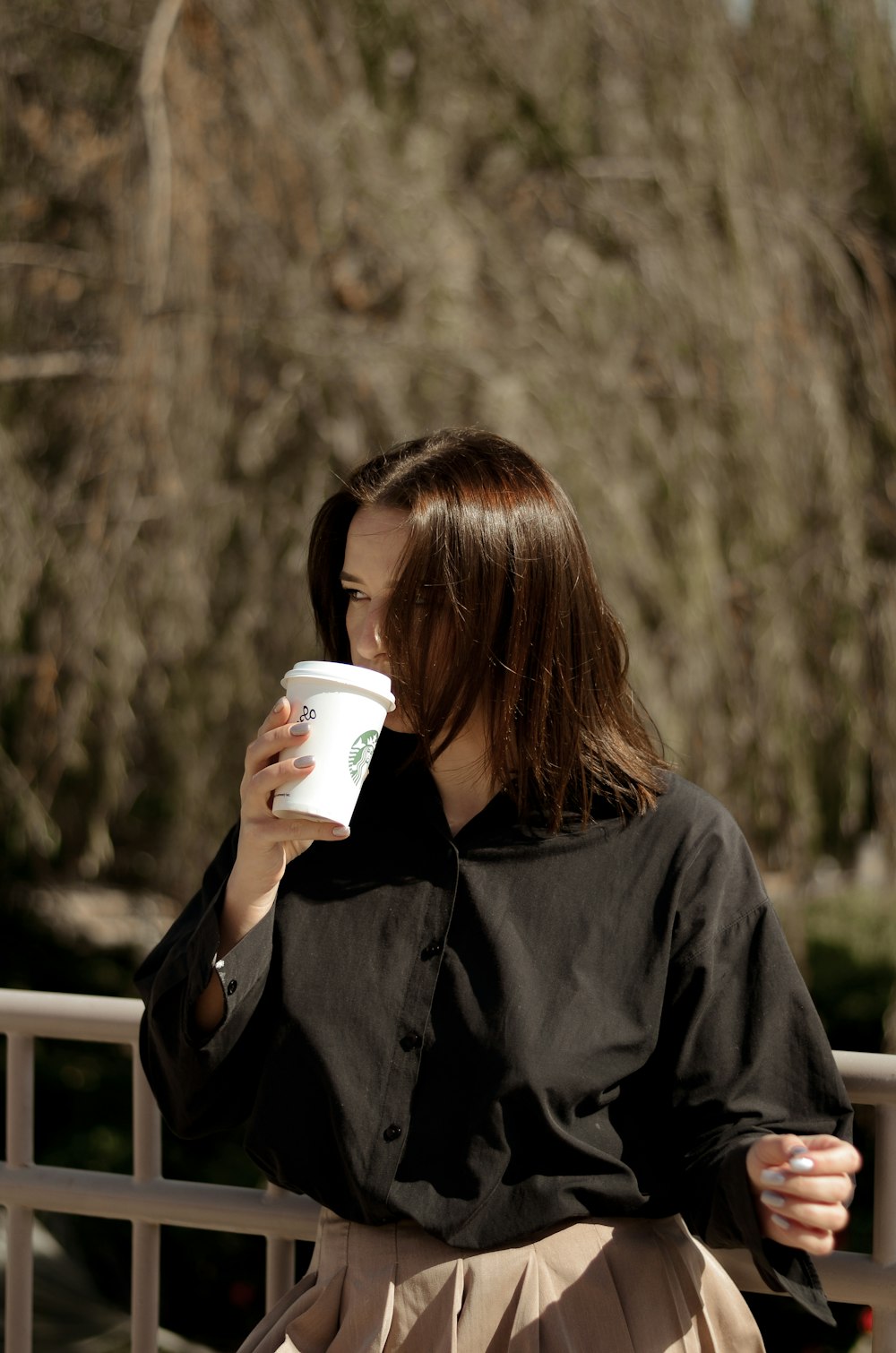 a woman holding a cup of coffee while sitting on a bench