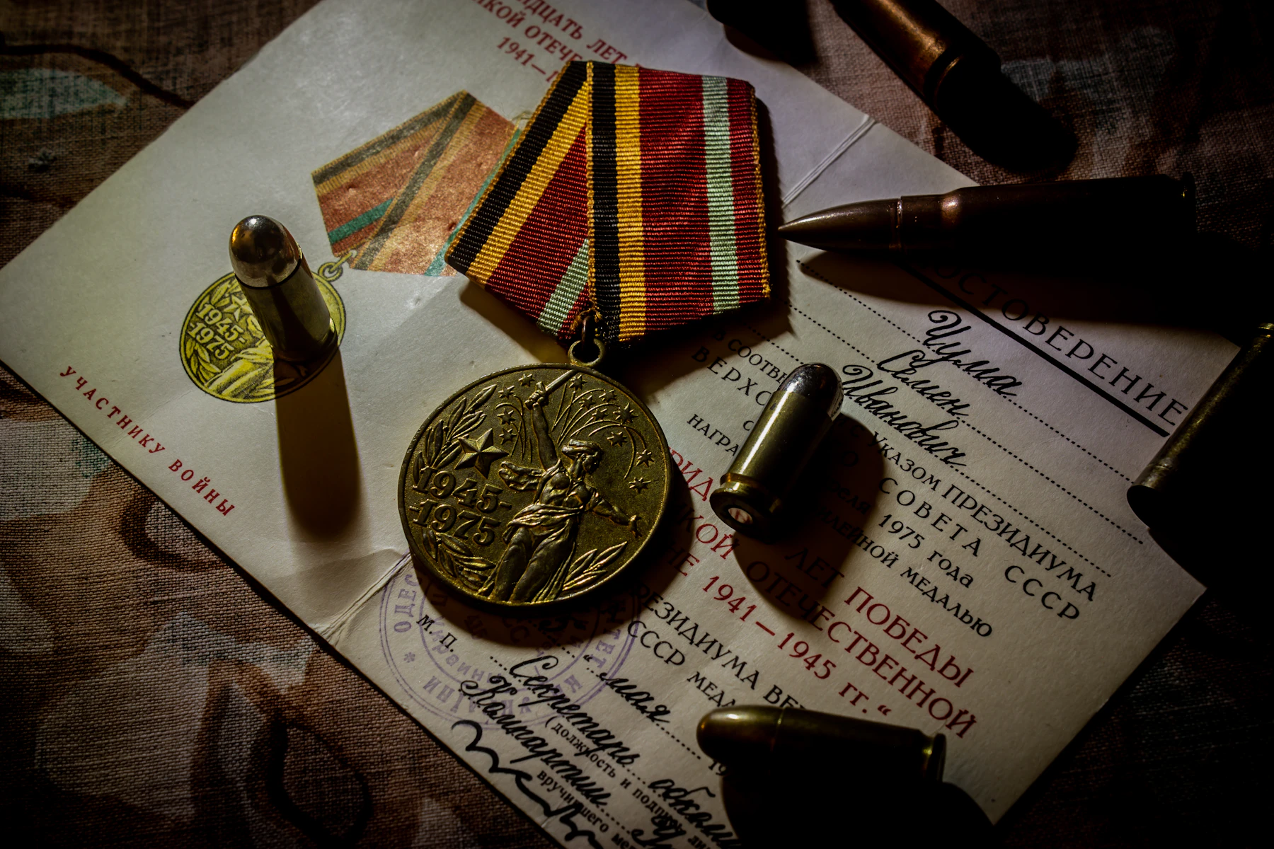 A brass medal on a striped ribbon lying on its printed award document