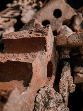 Close-up of stacked red bricks with rough textures under natural light.