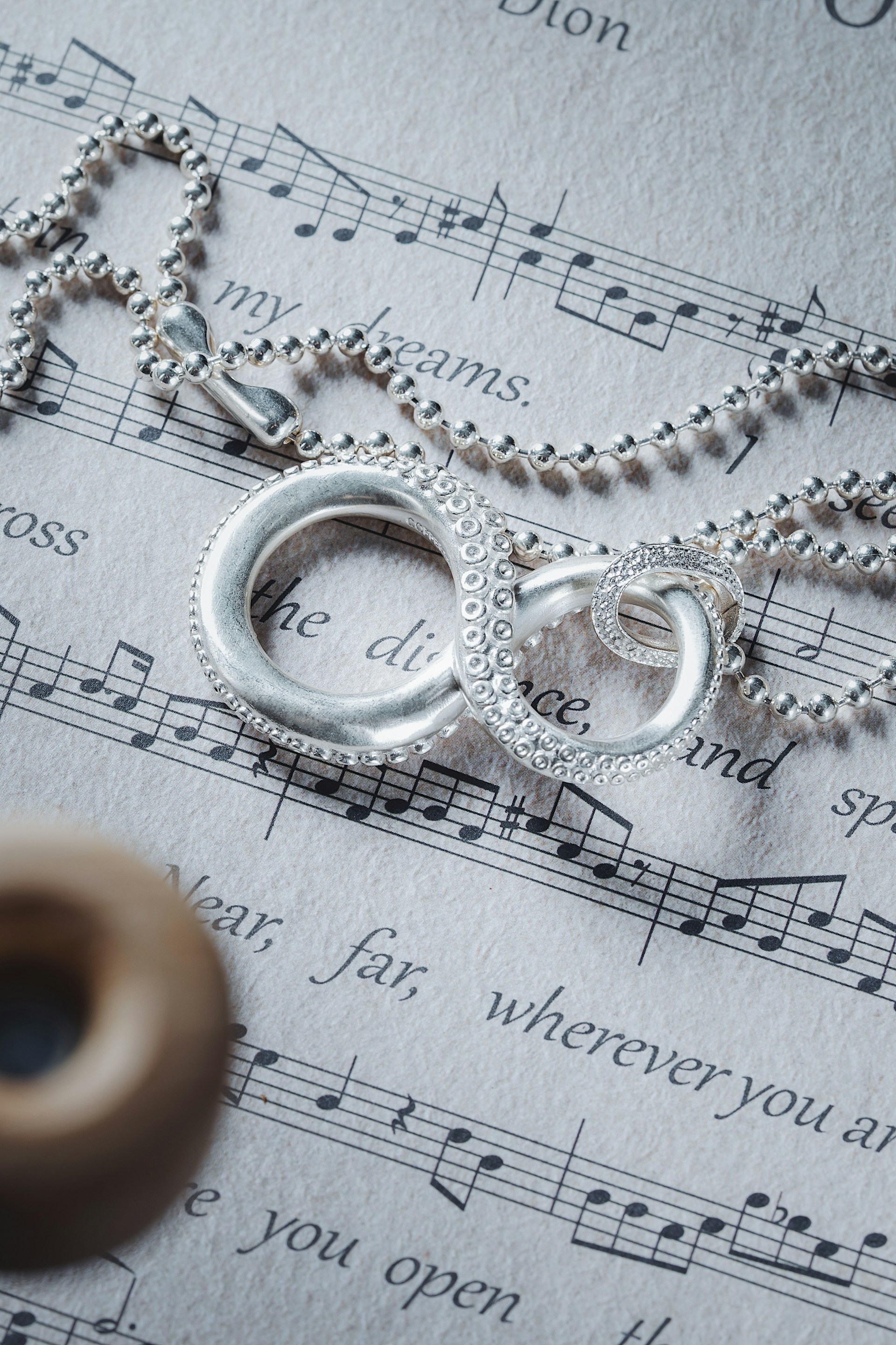 a close up of a necklace on a sheet of music