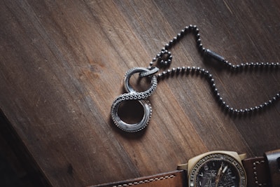 Artistic flat lay of rose gold hoops and a delicate chain necklace on a white marble surface.