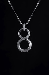 a silver necklace with two circles on a black background