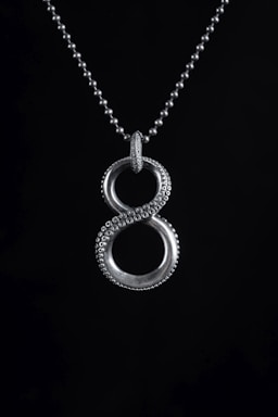a silver necklace with two circles on a black background