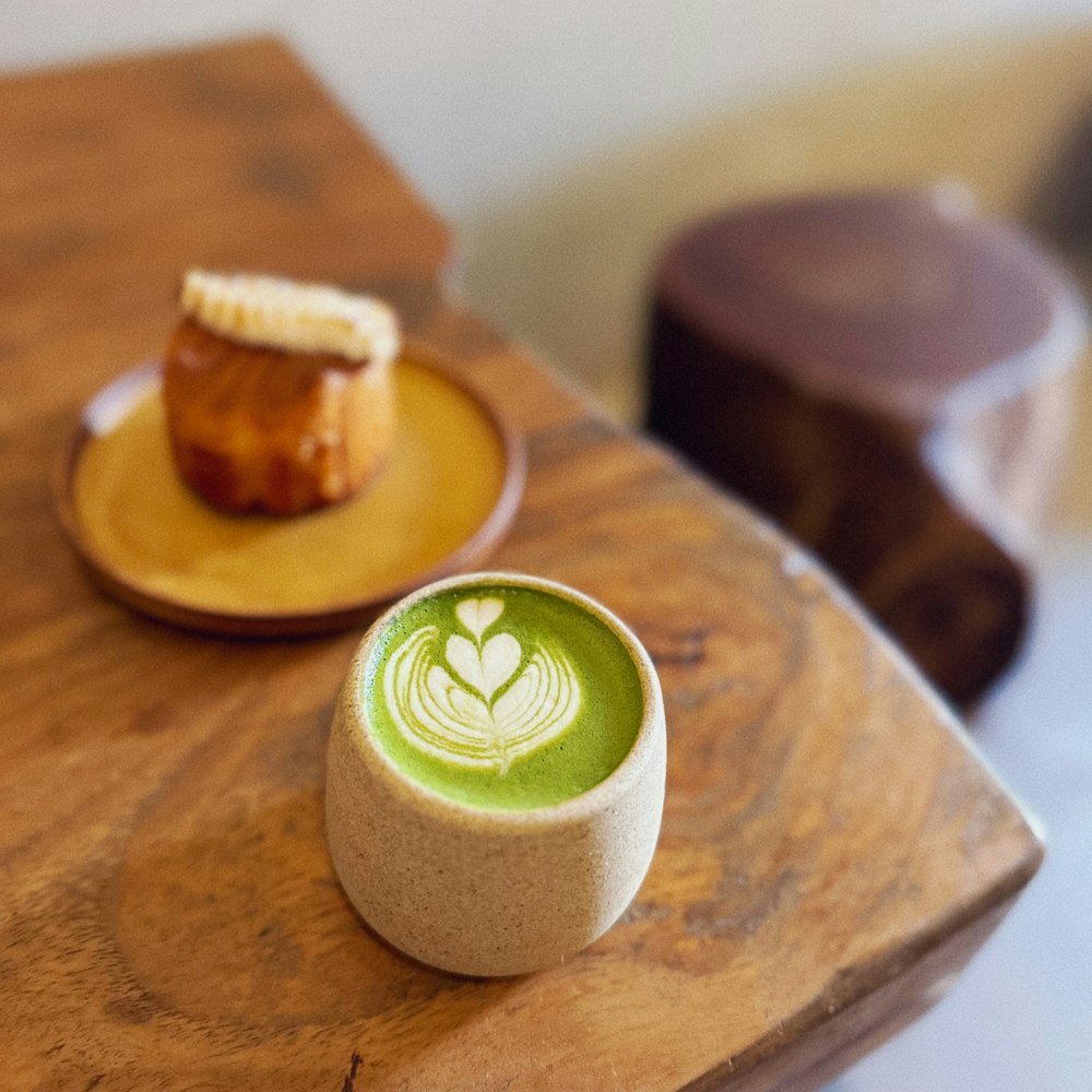 a small cup of green tea sits on a wooden table