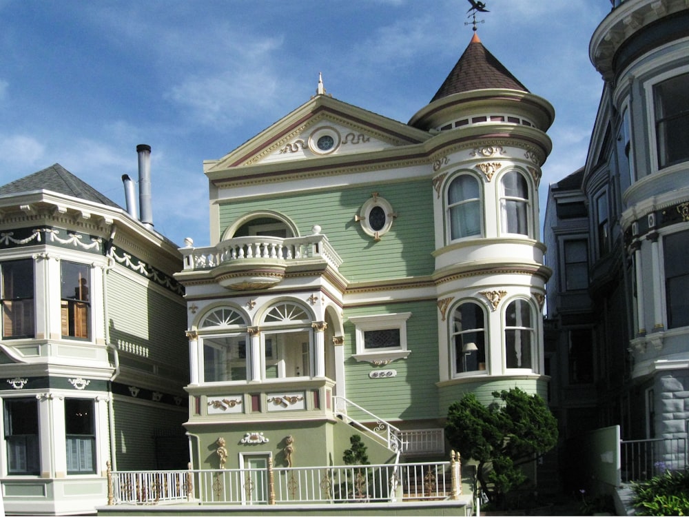 a large green house with a white balcony